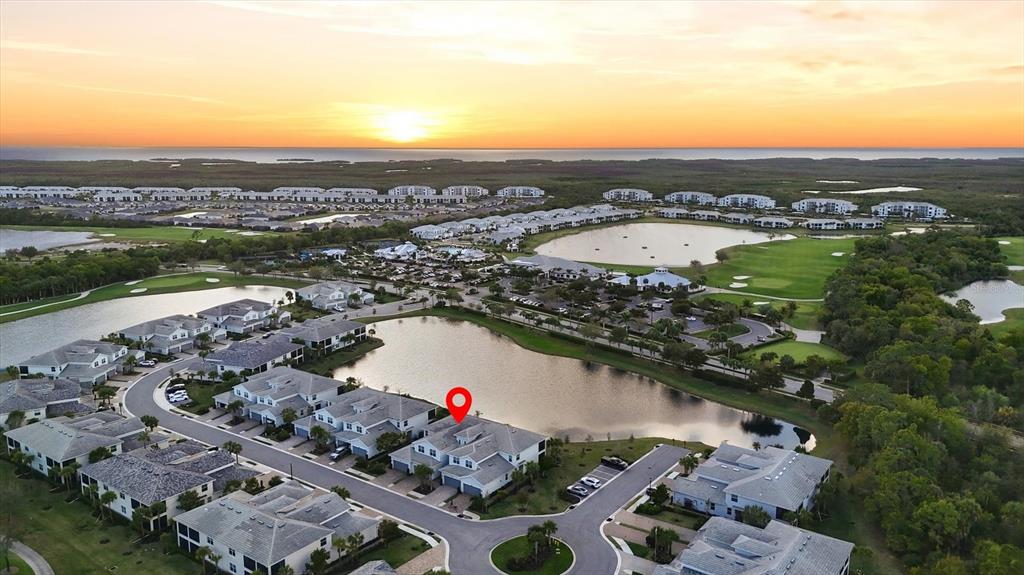 An aerial view shows a residential neighborhood with houses surrounding a lake at sunset — 14655 SYCAMORE COURT UNIT 3121, PUNTA GORDA, FL