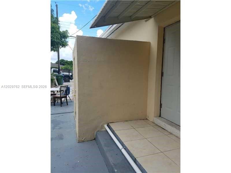 An exterior view shows a beige concrete wall next to a tiled entryway and door — 3240 NW 10th Ave, Miami FL 33127, MIAMI, FL