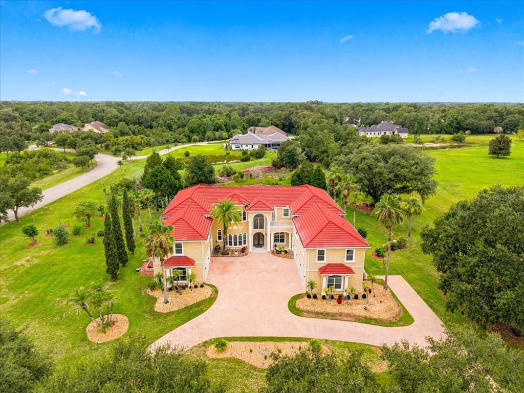 An aerial view of a large, two-story stucco house with a red tile roof — 19402 JACOBS RIVER RUN, LUTZ, FL