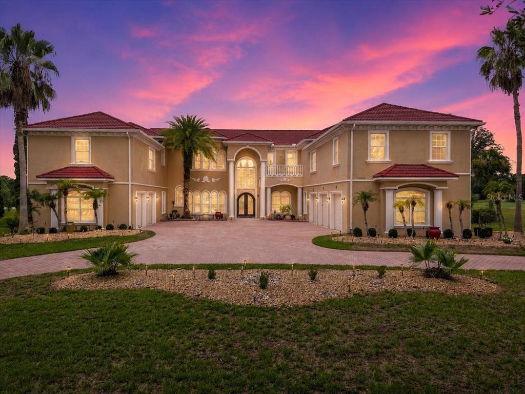 A large two-story Mediterranean-style house with a red tile roof and a paved circular driveway — 19402 JACOBS RIVER RUN, LUTZ, FL