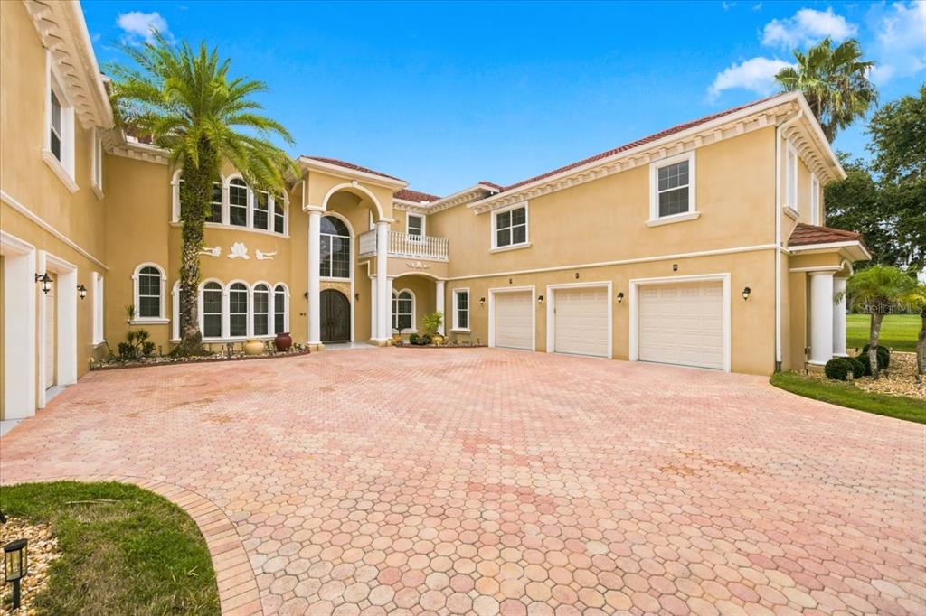 A large, two-story stucco house with a three-car garage and a paved circular driveway — 19402 JACOBS RIVER RUN, LUTZ, FL