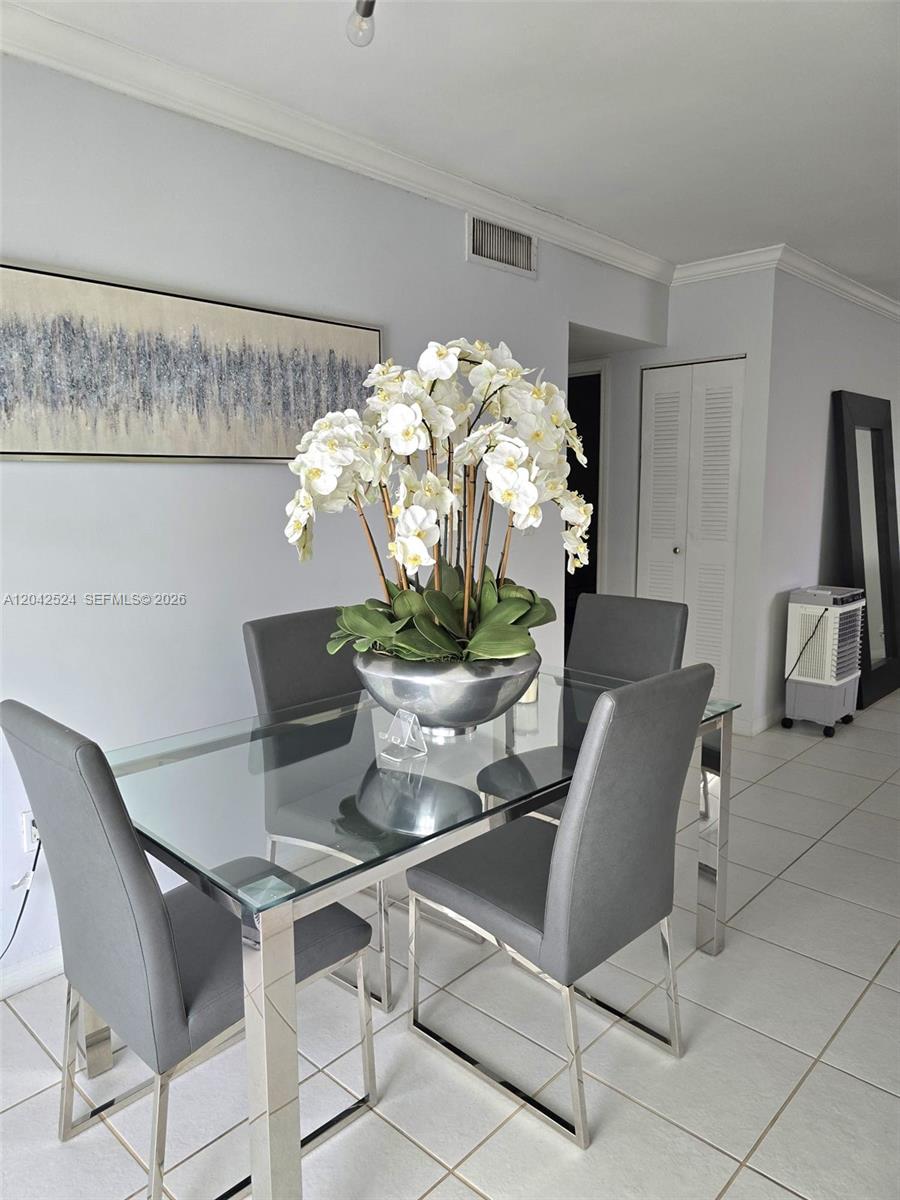 A dining area features a glass-topped table, four gray chairs, and a large orchid centerpiece — 1265 W 24th St # 201, Hialeah FL 33010, HIALEAH, FL