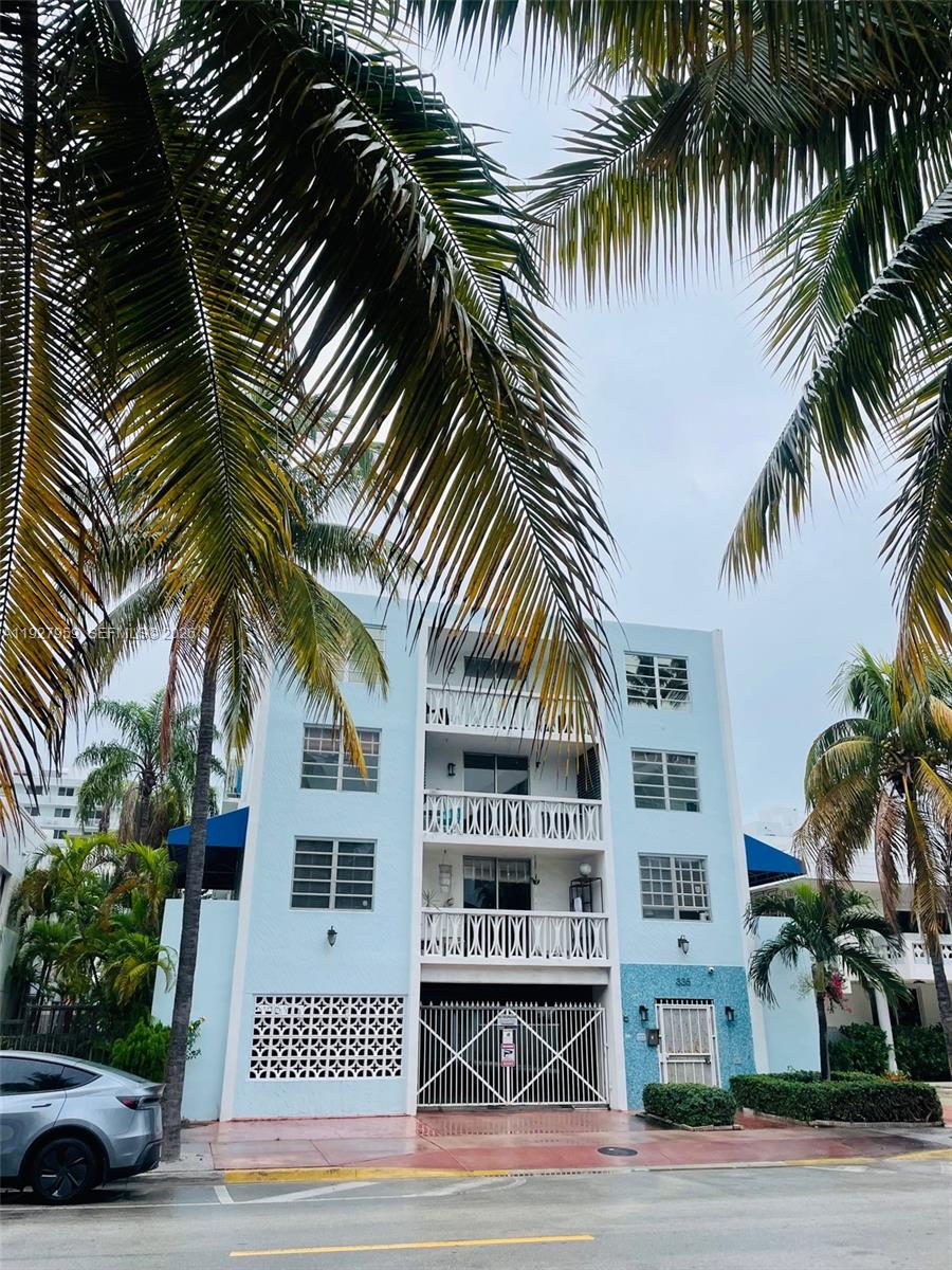 A light blue three-story apartment building with palm trees and a gated ground-level entrance — 335 Collins Ave # 302, Miami Beach FL 33139, MIAMI BEACH, FL