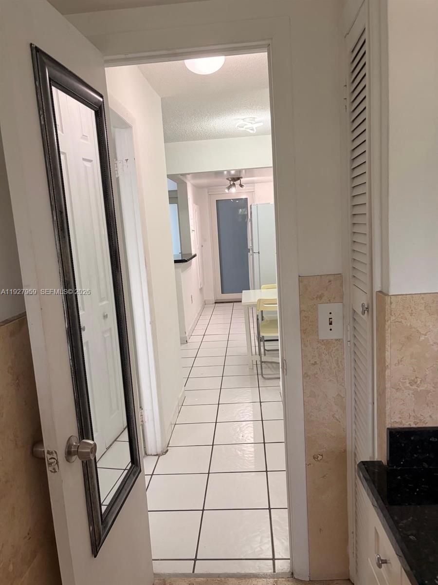 A view through a doorway shows a tiled hallway leading to a kitchen area — 335 Collins Ave # 302, Miami Beach FL 33139, MIAMI BEACH, FL