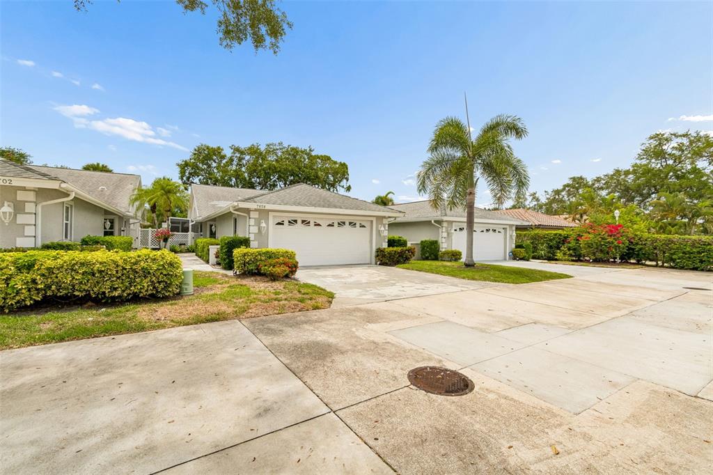 A view of two single-story residential houses with attached garages and manicured landscaping — 7656 PALM AIRE LANE, SARASOTA, FL