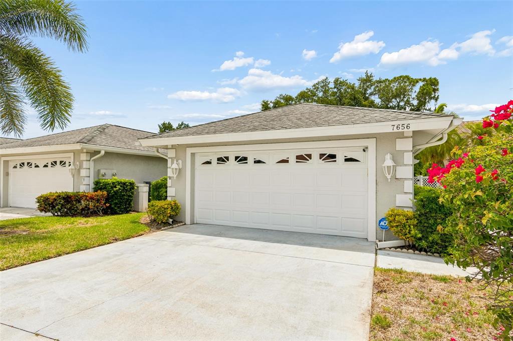 The exterior view shows a single-story house with a white garage door and a driveway — 7656 PALM AIRE LANE, SARASOTA, FL