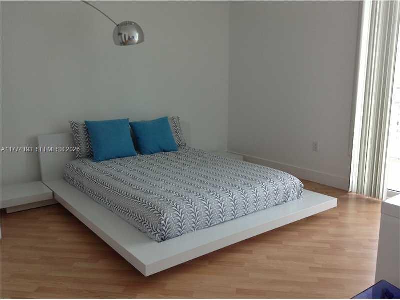 A bedroom features a low-profile white platform bed with a patterned cover and blue pillows — 350 NE 24th St # 1108, Miami FL 33137, MIAMI, FL