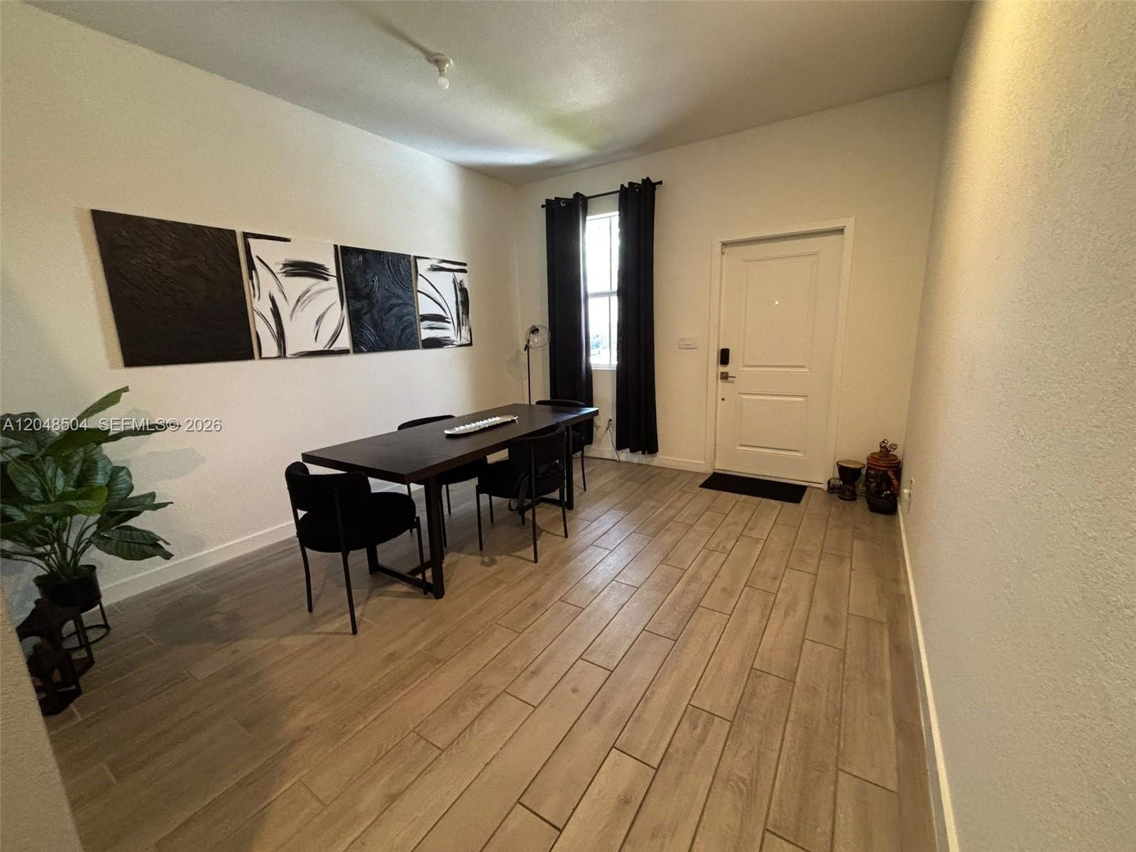 A dining room features a dark wood table, black chairs, and light wood-look tile flooring — 830 SE 19th St, Homestead FL 33034, HOMESTEAD, FL