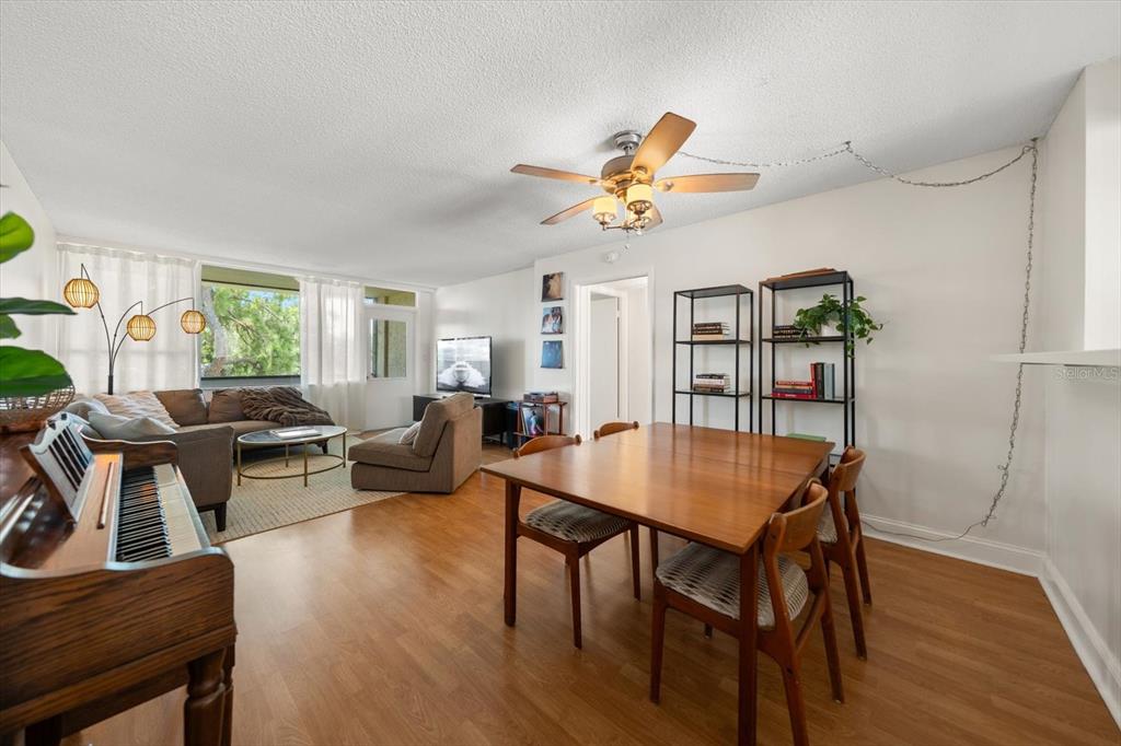 A living and dining area features wood-look flooring, a ceiling fan, and a piano — 2614 COVE CAY DRIVE UNIT 409, CLEARWATER, FL
