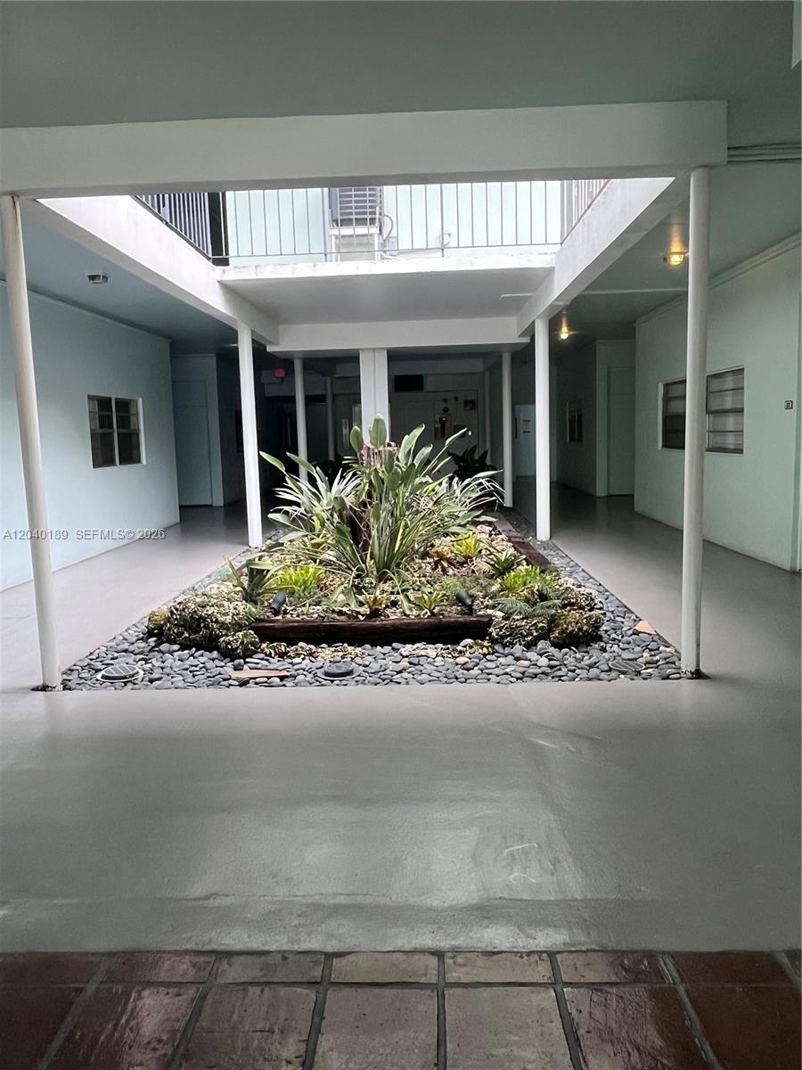 An open-air courtyard features a central garden bed with plants surrounded by gray stone — 2539 S Bayshore Dr # 320A, Miami FL 33133, MIAMI, FL