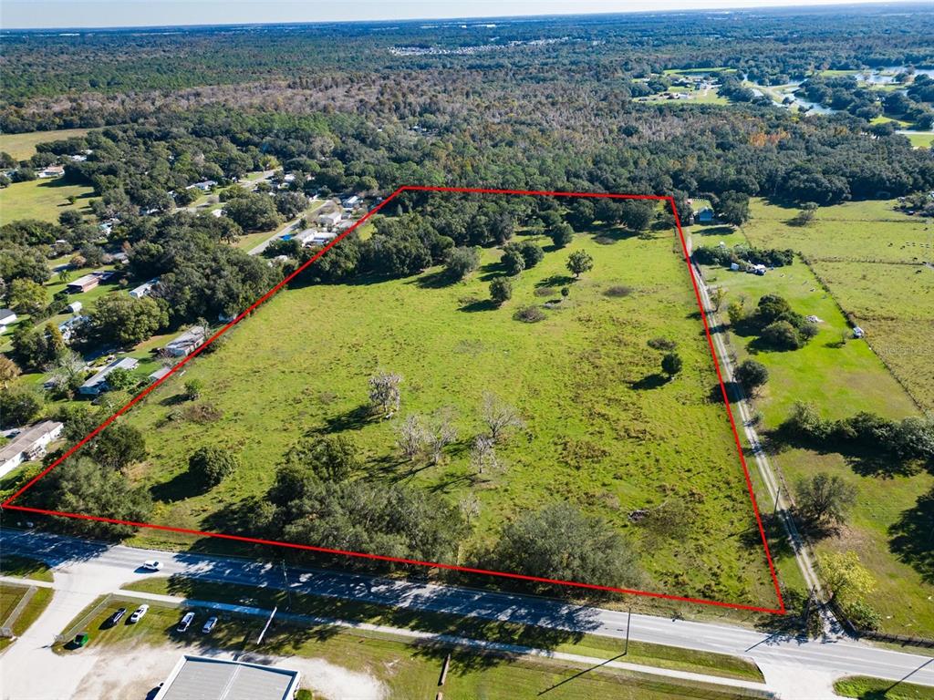 An aerial view shows a large, rectangular grassy lot outlined in red along a road — 1525 FISH HATCHERY ROAD, LAKELAND, FL