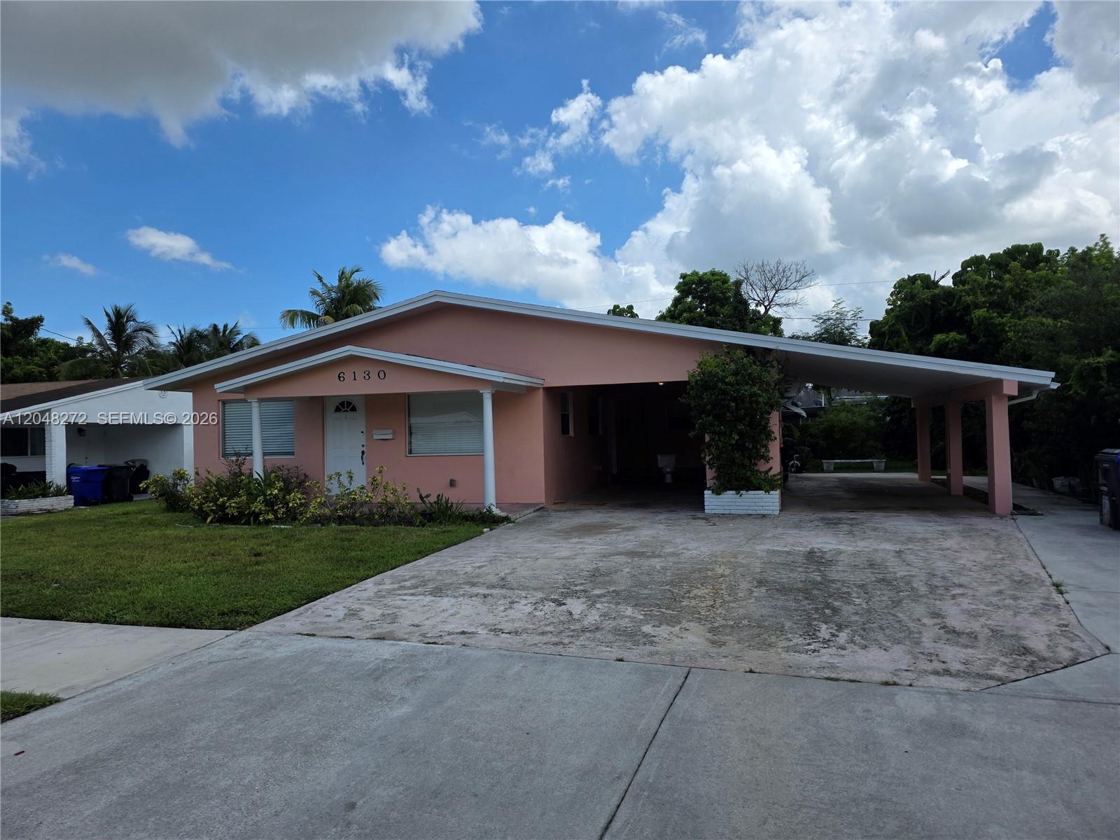 A pink single-story house features a large attached carport and a concrete driveway — 6130 Funston St, Hollywood FL 33023, HOLLYWOOD, FL