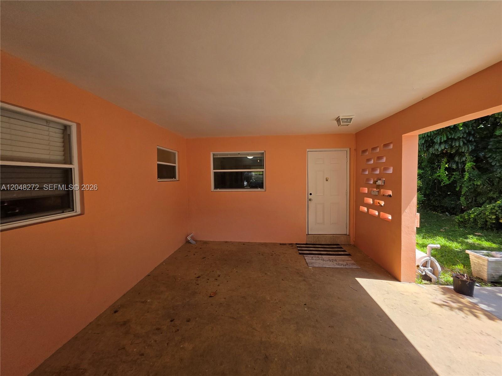 A covered concrete patio features peach-colored walls, a white door, and decorative breeze blocks — 6130 Funston St, Hollywood FL 33023, HOLLYWOOD, FL