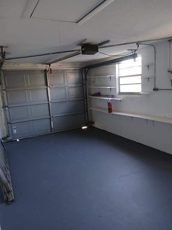 A garage with a gray painted floor, white walls, storage shelving, and a window — 1018 OSPREY COURT, DUNEDIN, FL