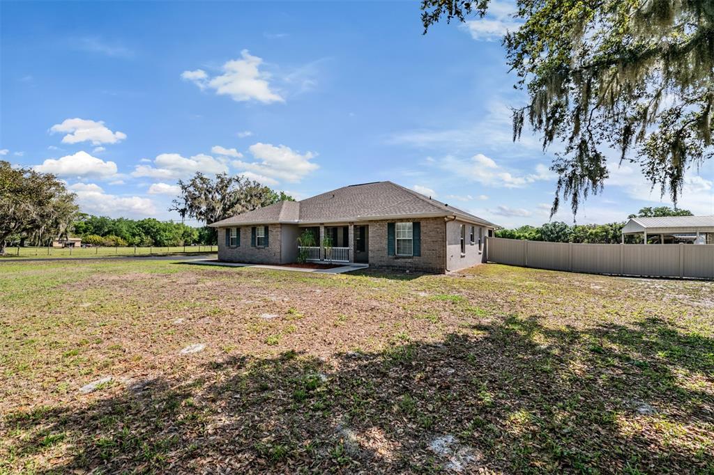 A single-story brick house with a covered porch sits on a large, grassy lot — 17216 ALDERMAN TURNER ROAD, WIMAUMA, FL