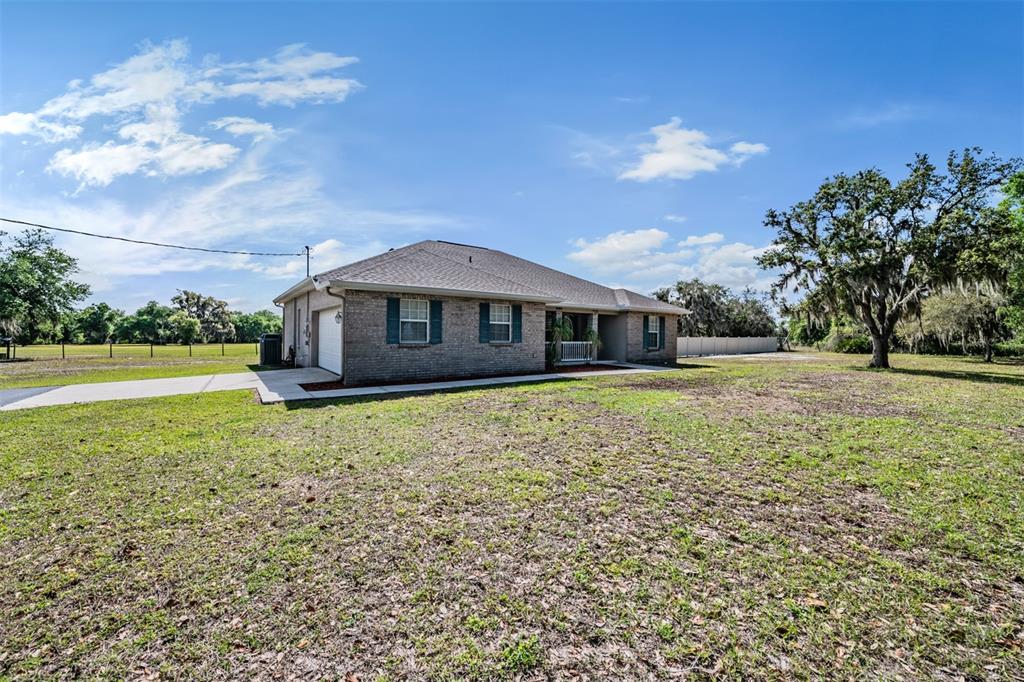A single-story brick house with a garage and a large, grassy yard — 17216 ALDERMAN TURNER ROAD, WIMAUMA, FL