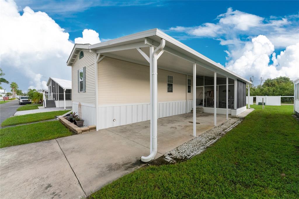 A light-colored mobile home features a concrete driveway, a covered carport, and a screened porch — 4300 RIVERSIDE DRIVE UNIT 137, PUNTA GORDA, FL