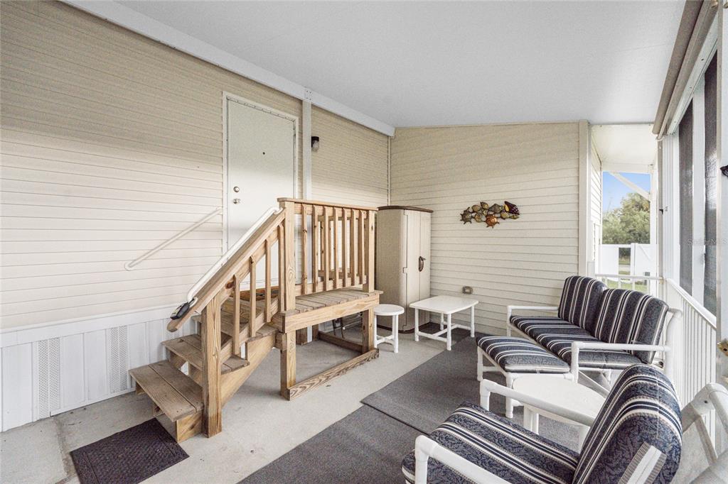 A covered porch features a wooden staircase leading to a door, outdoor furniture, and siding — 4300 RIVERSIDE DRIVE UNIT 137, PUNTA GORDA, FL