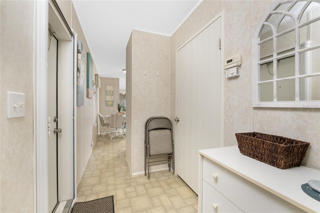 A hallway with light-colored walls, vinyl flooring, a folding chair, and a white dresser — 4300 RIVERSIDE DRIVE UNIT 137, PUNTA GORDA, FL