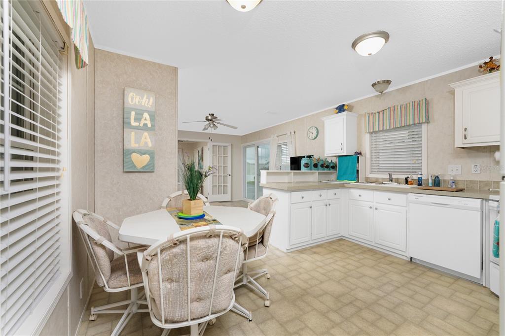 A kitchen and dining area with white cabinets, a round table, and light-colored tile flooring — 4300 RIVERSIDE DRIVE UNIT 137, PUNTA GORDA, FL
