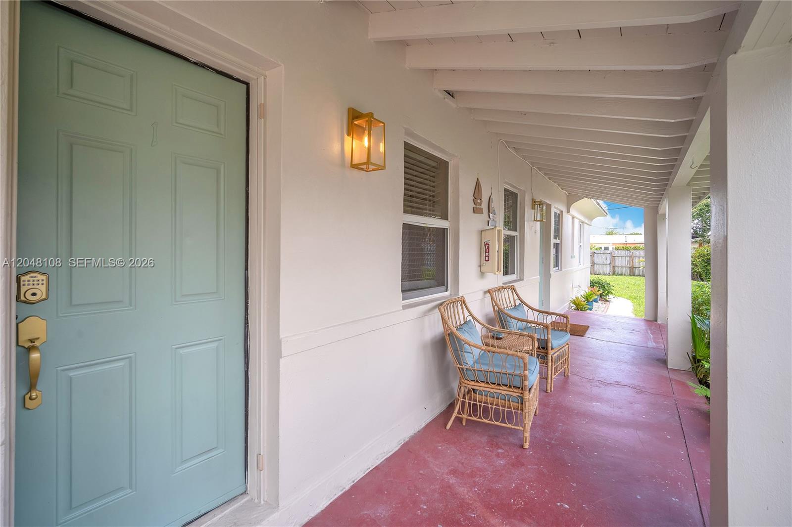 A covered porch with a light blue door, two wicker chairs, and red flooring — 261 SW 15th St # 2, Dania Beach FL 33004, DANIA BEACH, FL