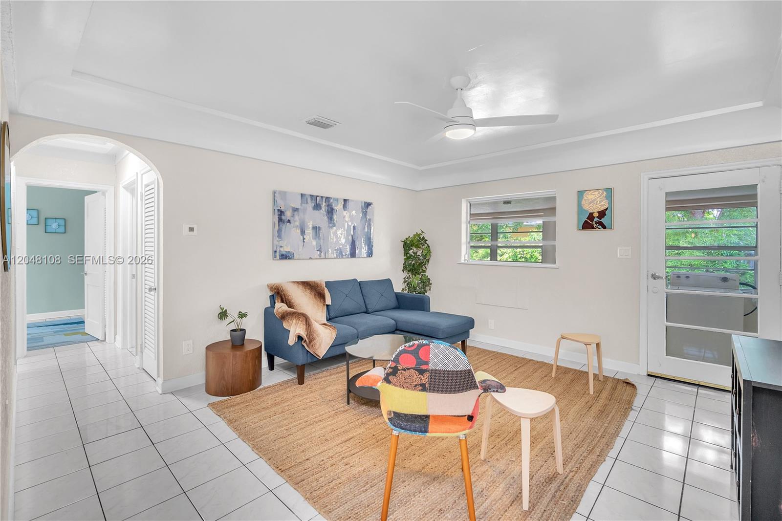 A living room features a blue sectional sofa, a jute rug, and white tile floors — 261 SW 15th St # 2, Dania Beach FL 33004, DANIA BEACH, FL