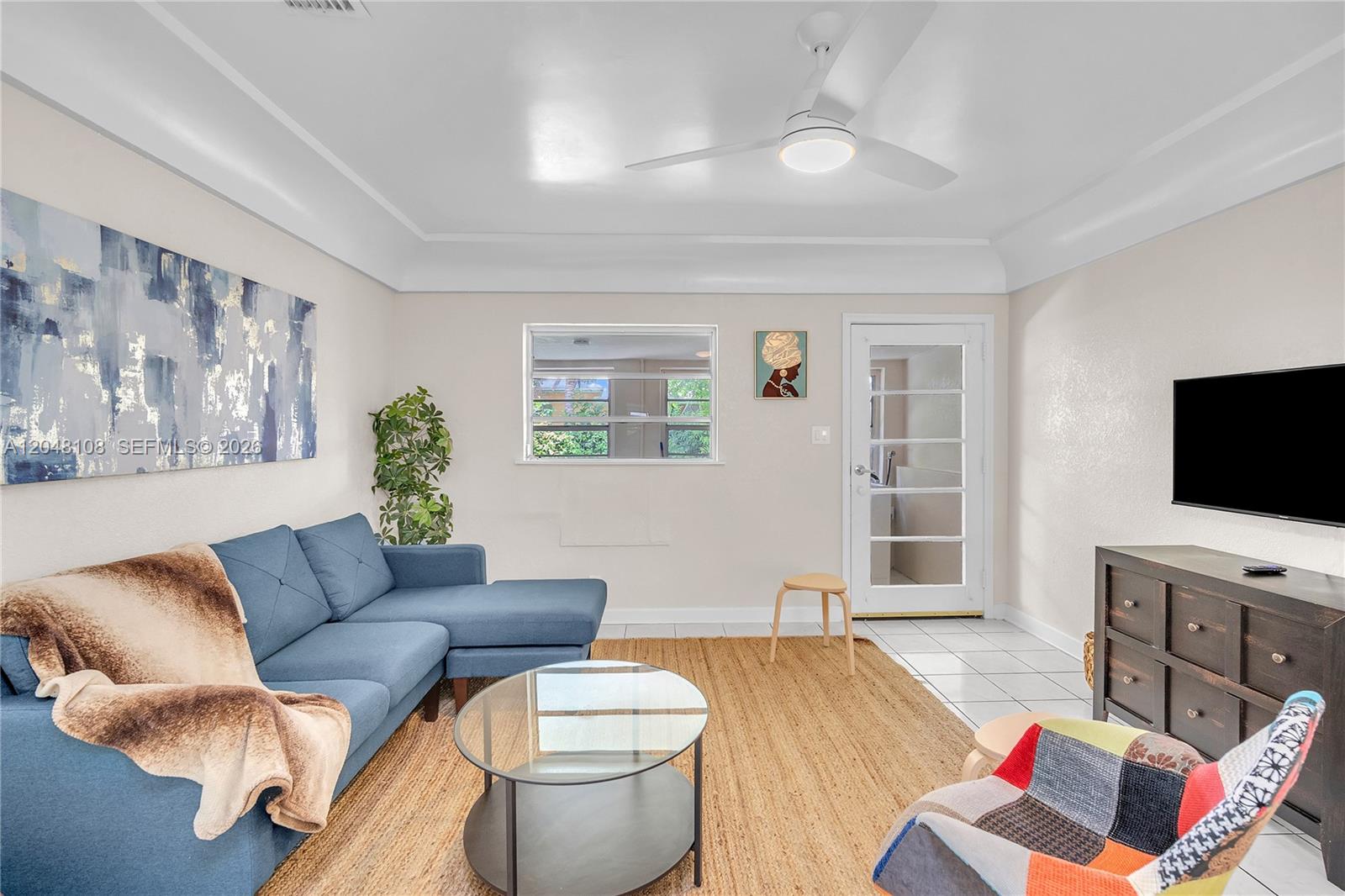 A living room features a blue sectional sofa, a glass coffee table, and tile flooring — 261 SW 15th St # 2, Dania Beach FL 33004, DANIA BEACH, FL