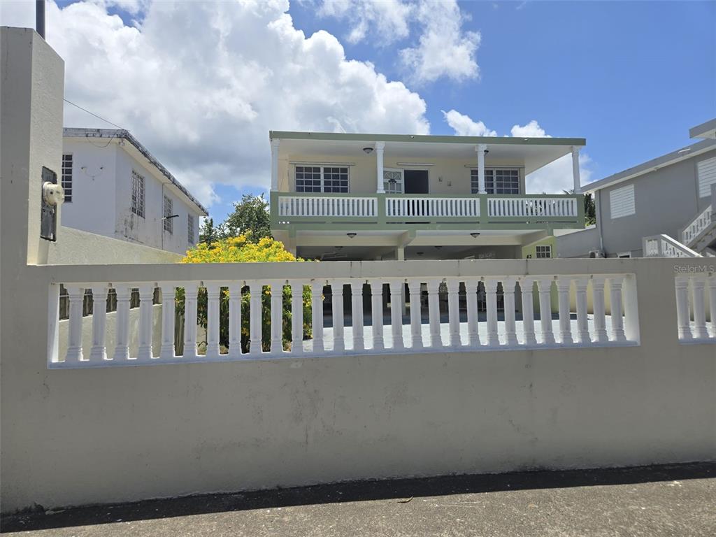 A two-story house with a balcony is viewed from behind a concrete balustrade fence — 43 VILLA PESQUERA UNIT 43, PATILLAS, PR