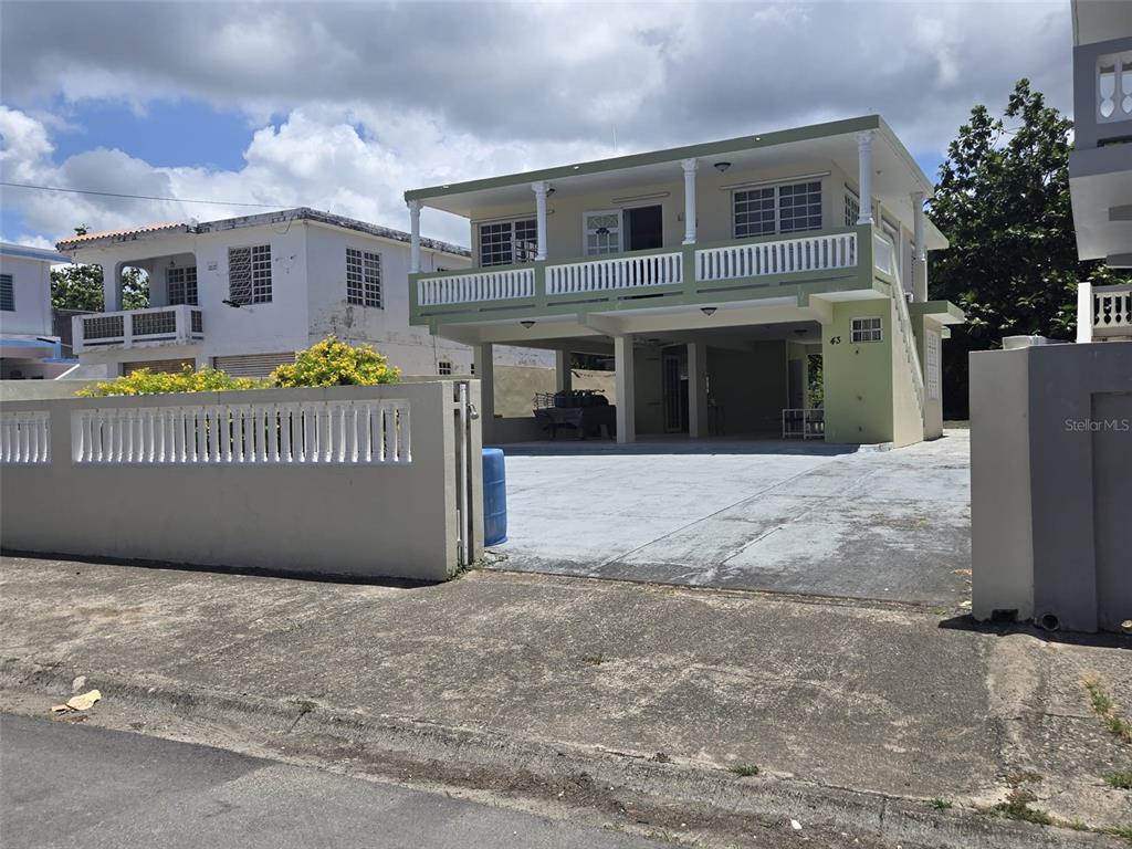 A two-story house with a balcony, open ground-level parking, and a concrete perimeter fence — 43 VILLA PESQUERA UNIT 43, PATILLAS, PR