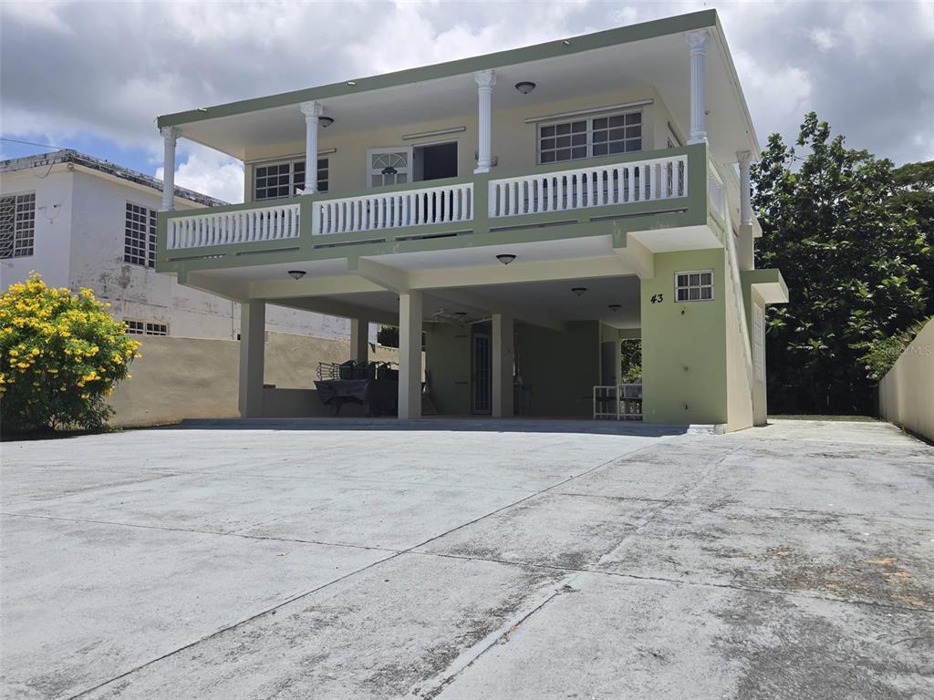 A two-story house with a raised living area, a balcony, and a large concrete driveway — 43 VILLA PESQUERA UNIT 43, PATILLAS, PR