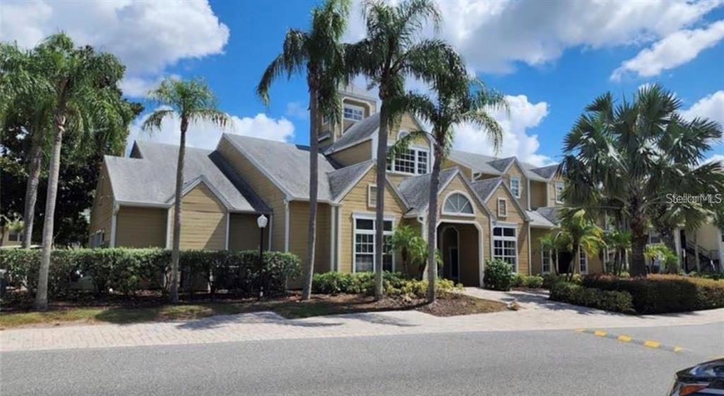 A two-story tan building with a shingled roof is surrounded by palm trees and landscaping — 1025 S HIAWASSEE ROAD UNIT 2216, ORLANDO, FL
