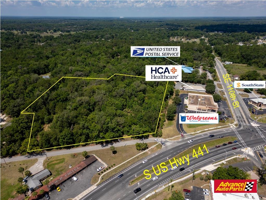An aerial view shows a vacant, tree-covered lot outlined in yellow near a highway intersection — 11090 SE 55TH AVENUE ROAD, BELLEVIEW, FL