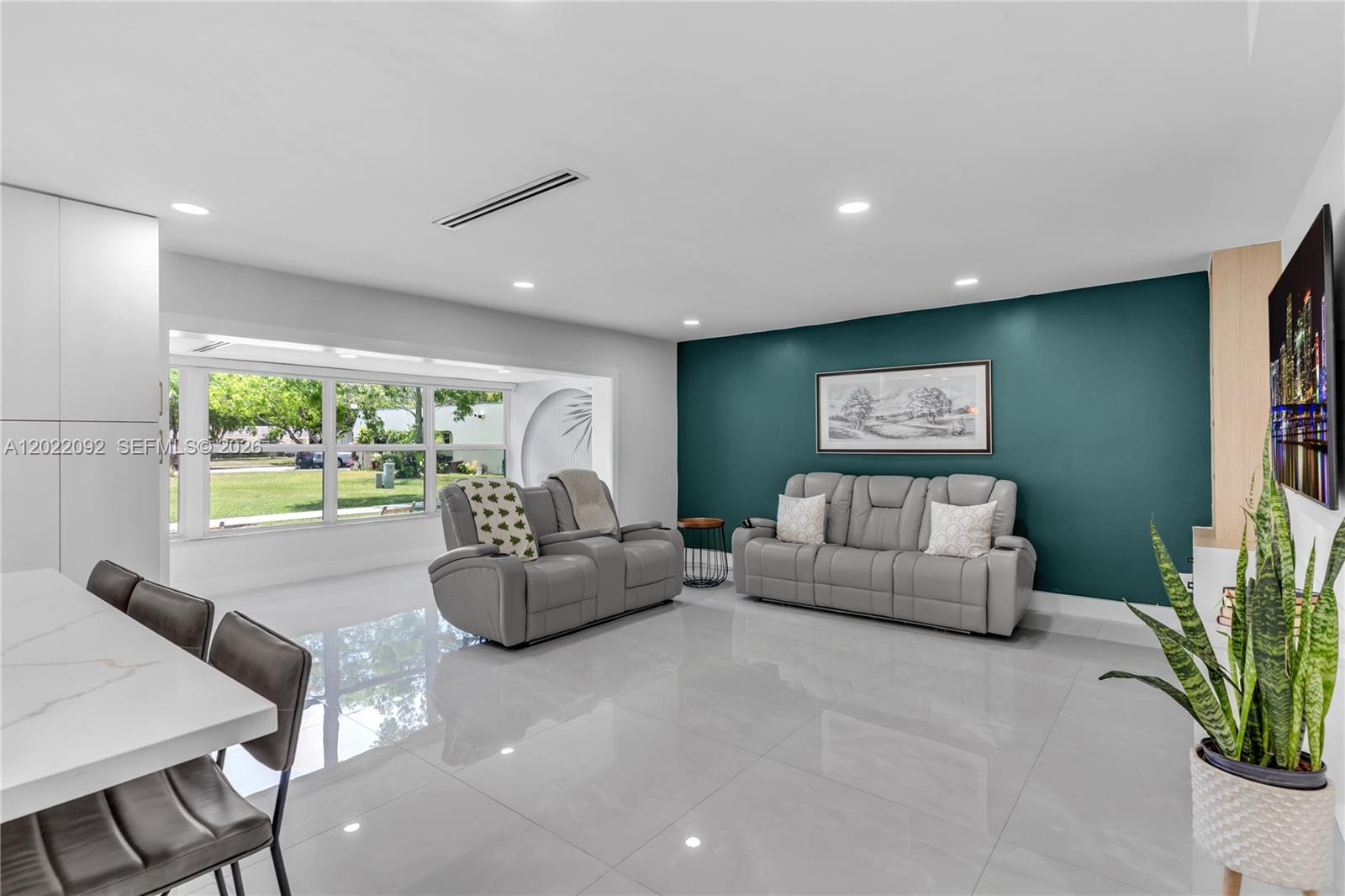 A living room features a teal accent wall, gray leather sofas, and large windows — 17105 SW 113th Ct # 11531E, Miami FL 33157, MIAMI, FL