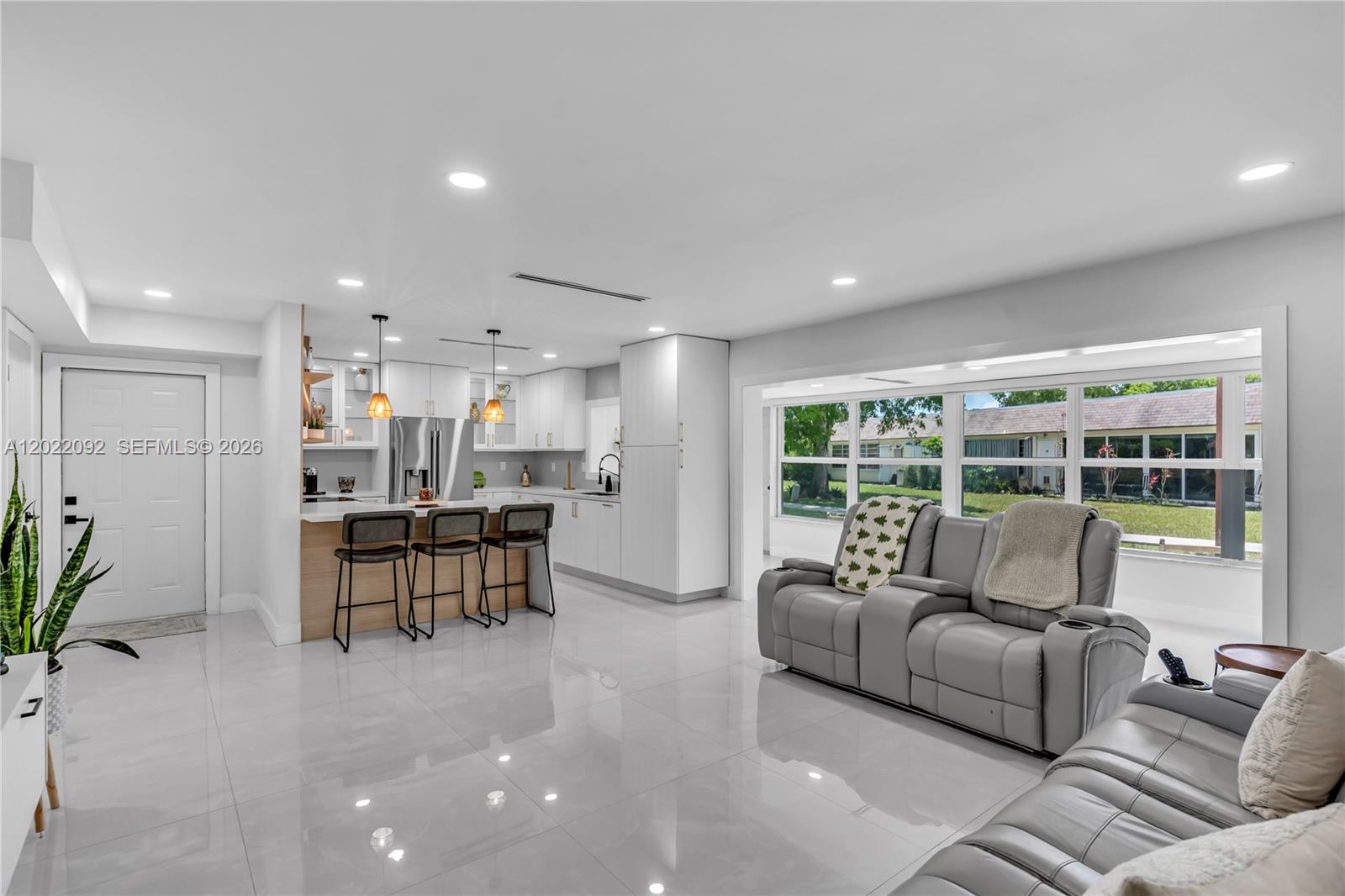 A modern open-concept kitchen and living area features white cabinetry, tile flooring, and gray furniture — 17105 SW 113th Ct # 11531E, Miami FL 33157, MIAMI, FL
