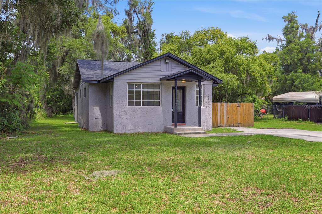A single-story gray house with a front porch stands on a grassy lot — 210 WINSLOW AVENUE, DELAND, FL