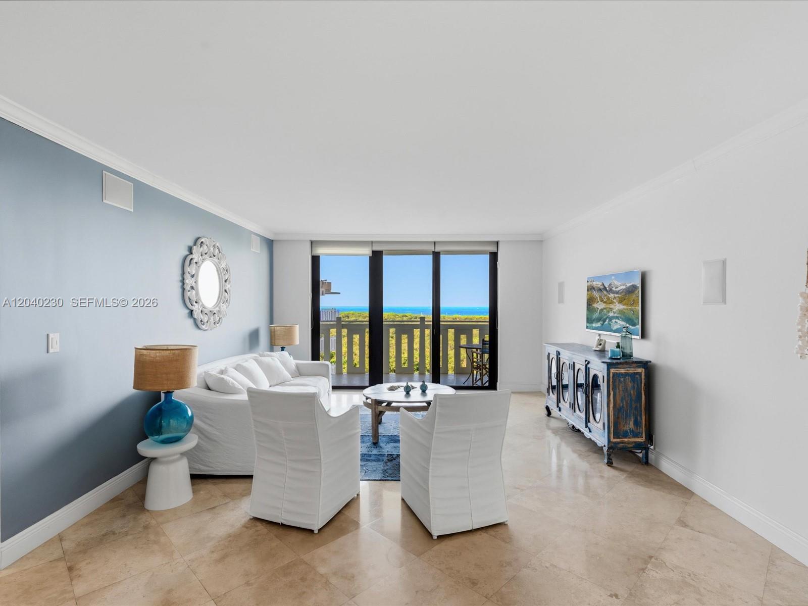 A living room features white furniture, a blue accent wall, and a balcony overlooking the ocean — 1121 Crandon Blvd # E1205, Key Biscayne FL 33149, KEY BISCAYNE, FL