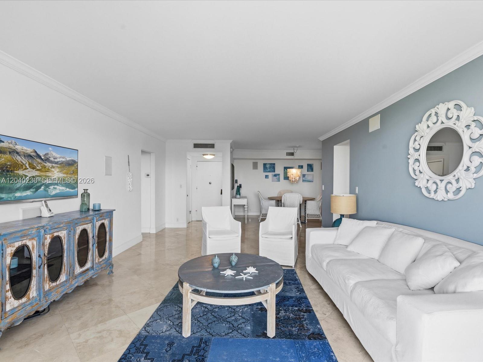 A living room features a white sofa, blue accent wall, round coffee table, and television — 1121 Crandon Blvd # E1205, Key Biscayne FL 33149, KEY BISCAYNE, FL