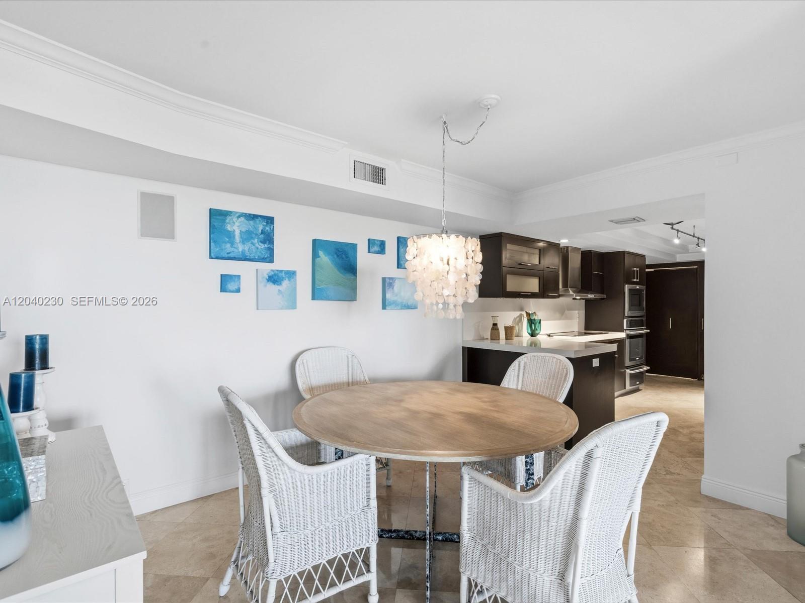 A dining area features a round wooden table, white wicker chairs, and a shell chandelier — 1121 Crandon Blvd # E1205, Key Biscayne FL 33149, KEY BISCAYNE, FL