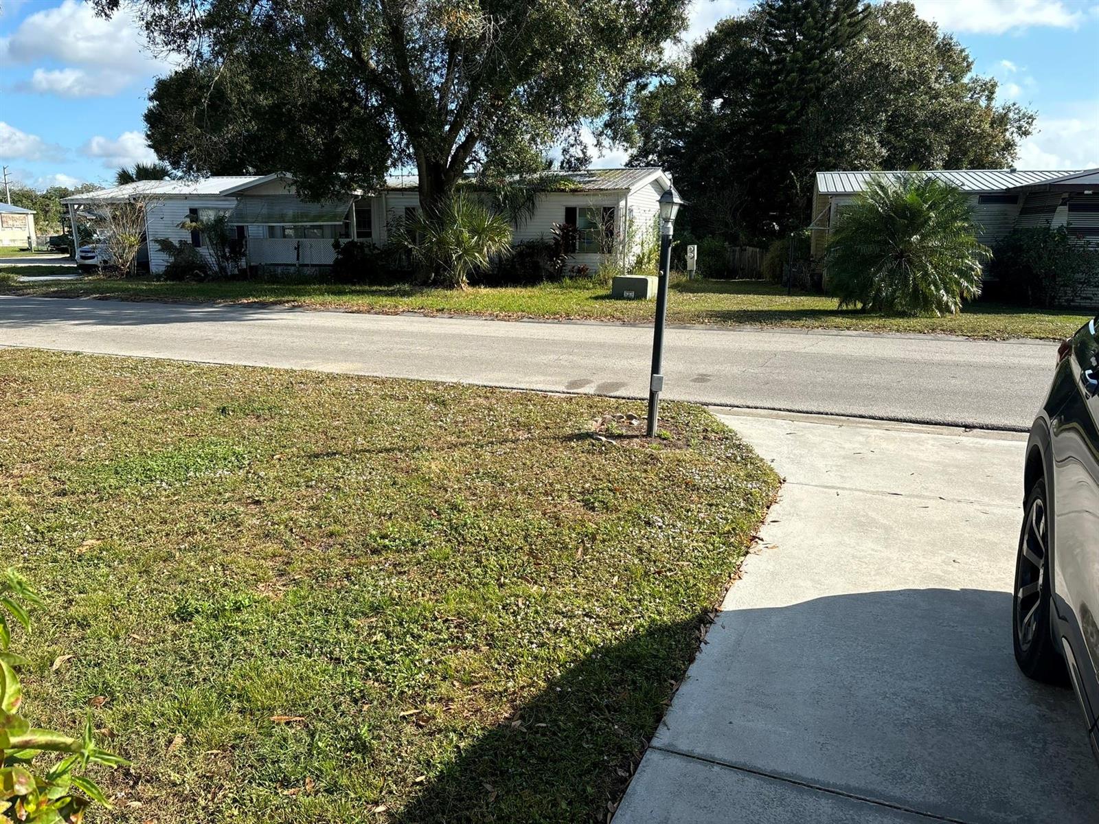 A view of a street with mobile homes, a lamp post, and a driveway — 111 NE 8th Avenue, Okeechobee FL 34972, OKEECHOBEE, FL