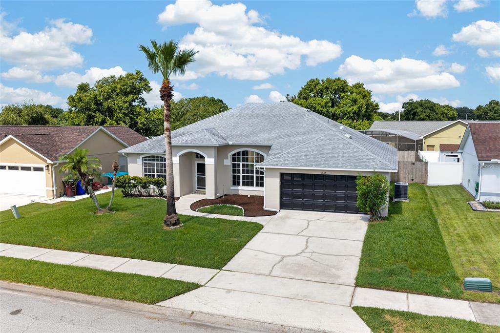 A single-story suburban house with a gray roof, beige stucco siding, and a two-car garage — 3832 BLACKBERRY CIRCLE, ST CLOUD, FL