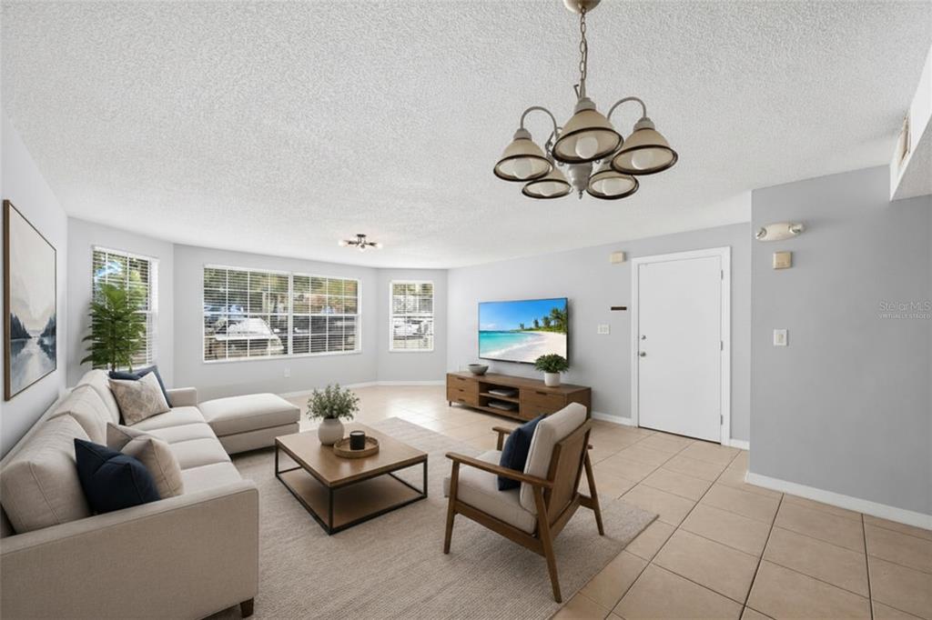 A living room with tile floors, a sectional sofa, a television, and a chandelier — 2723 N POINCIANA BOULEVARD UNIT 153, KISSIMMEE, FL