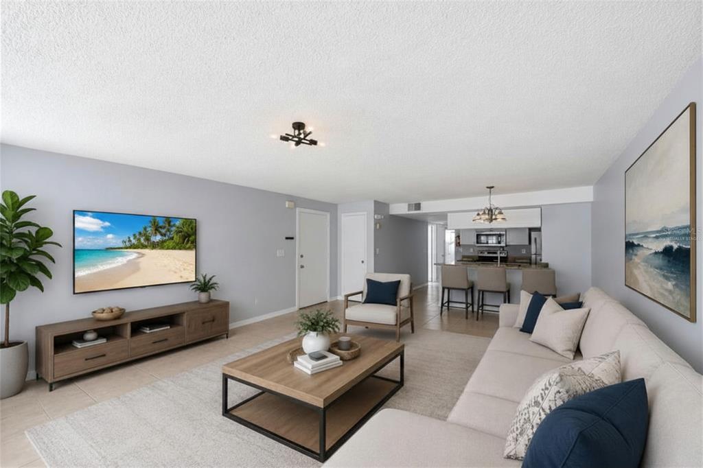 A living room with light gray walls, a beige sectional sofa, and an open kitchen — 2723 N POINCIANA BOULEVARD UNIT 153, KISSIMMEE, FL