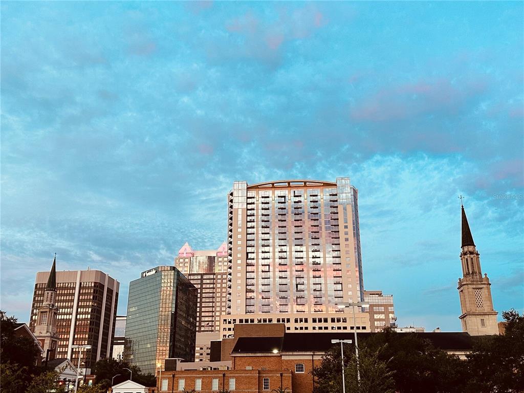 A view of a city skyline featuring several high-rise buildings and two church steeples — 155 S COURT AVENUE UNIT 1415, ORLANDO, FL