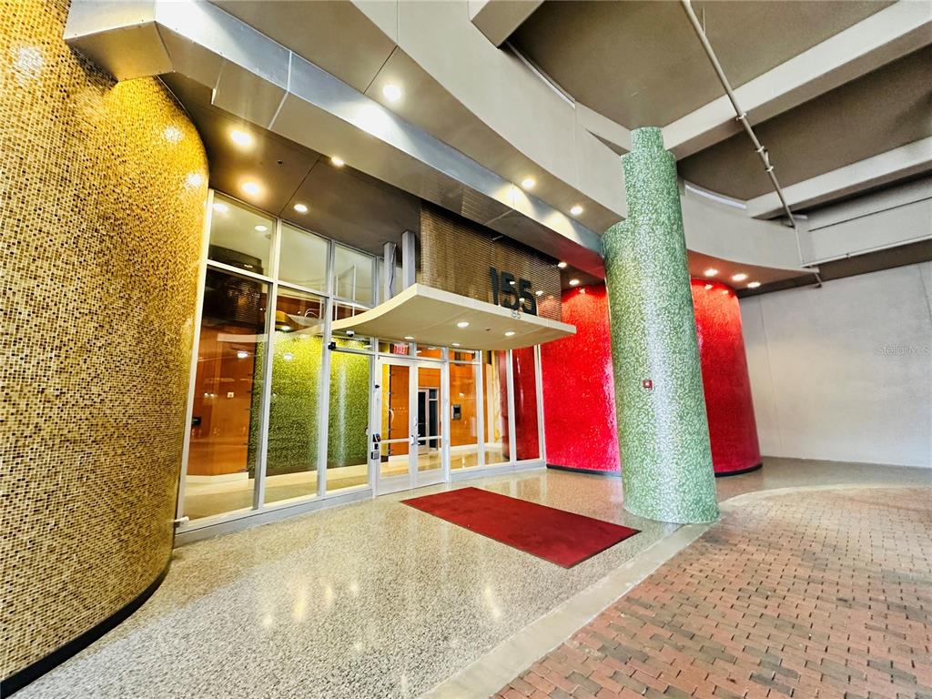 The entrance to a building features a glass door, mosaic-tiled walls, and a brick floor — 155 S COURT AVENUE UNIT 1415, ORLANDO, FL