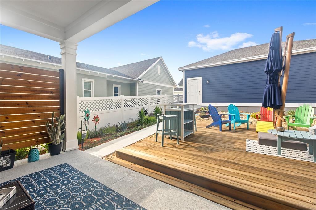 A backyard patio features a wooden deck, colorful Adirondack chairs, and a white privacy fence — 1234 CANYON CREEK TRAIL, WINTER GARDEN, FL