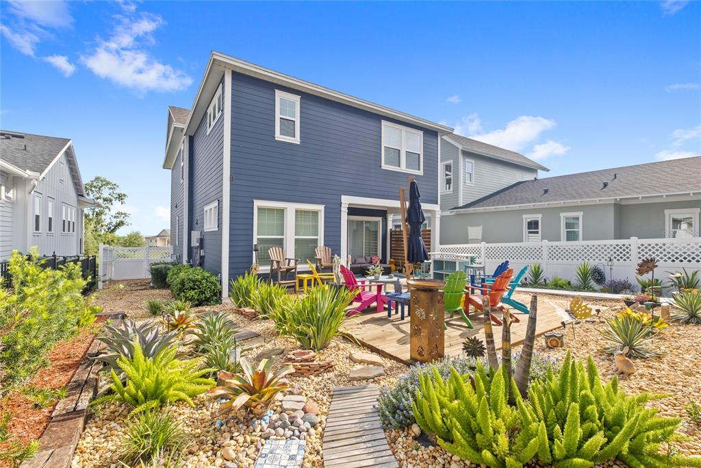 A blue two-story house features a backyard patio with colorful chairs and xeriscaped landscaping — 1234 CANYON CREEK TRAIL, WINTER GARDEN, FL