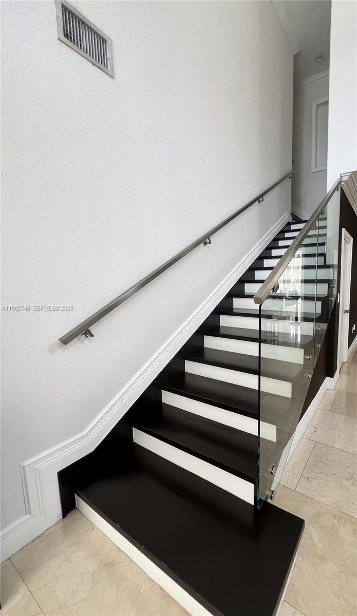 A staircase features dark wood treads, white risers, and a glass railing with a handrail — 5513 SW 164th Ct, Miami FL 33185, MIAMI, FL