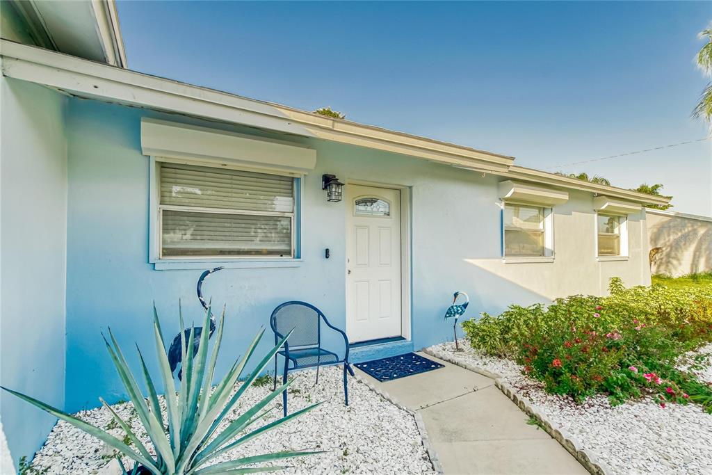 The exterior of a light blue house features a white front door and landscaping — 6004 GOLF AND SEA BOULEVARD, APOLLO BEACH, FL