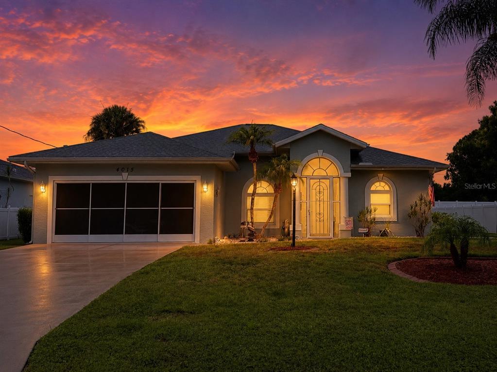 A single-story house with a garage and arched windows stands under a vibrant sunset sky — 4015 CLEARFIELD STREET, NORTH PORT, FL