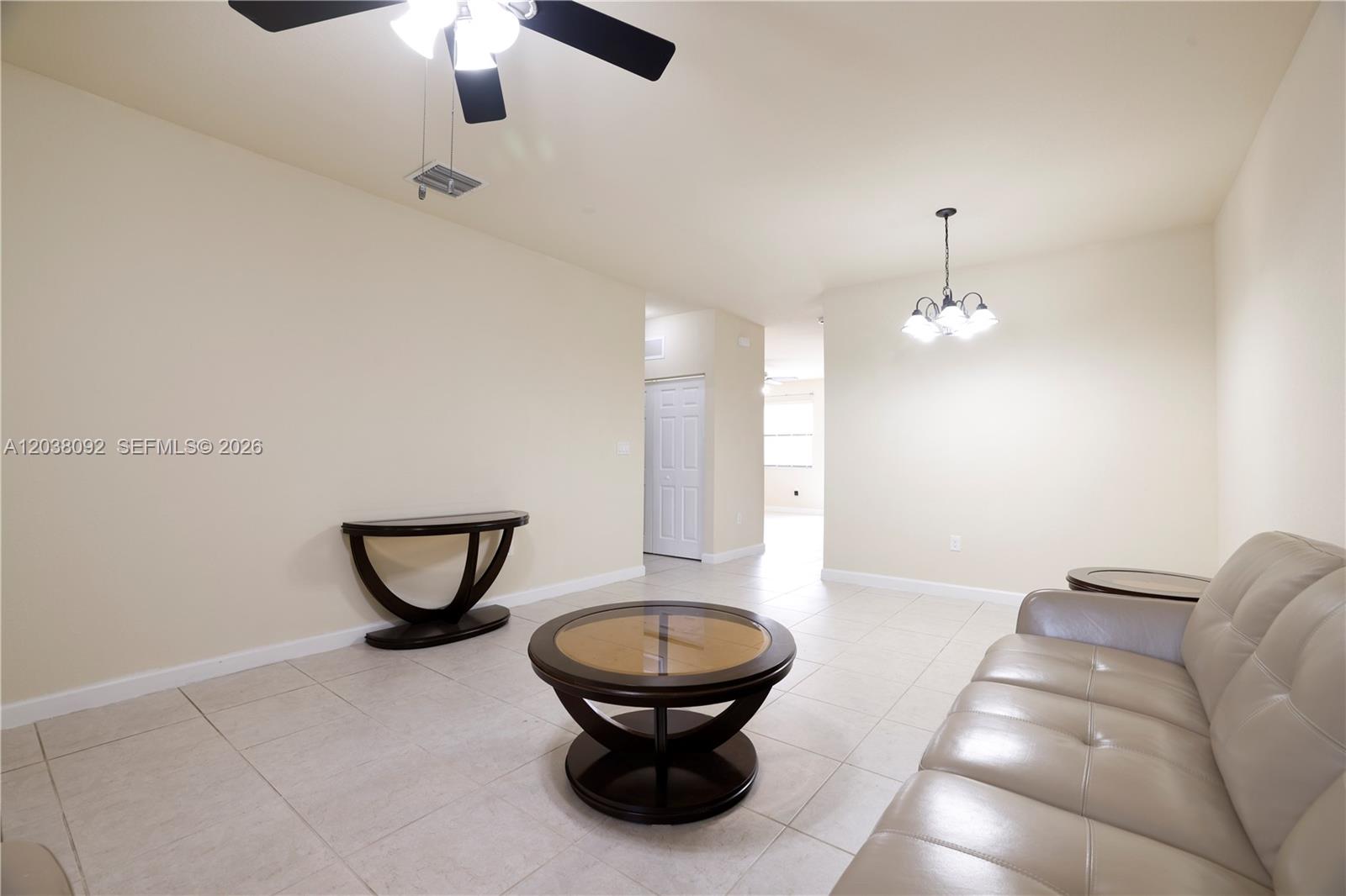 A living room features beige tile flooring, light walls, a ceiling fan, and dark furniture — 7146 SW 163rd Ave, Miami FL 33193, MIAMI, FL